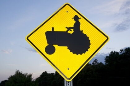 Rural road sign indicating tractors in the area