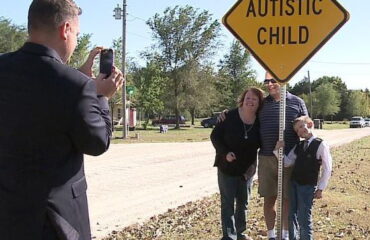 Family standing next to an autism sign for young boy.