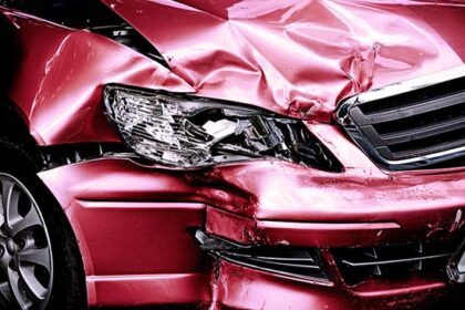 Red car with damage from auto accident in common places.