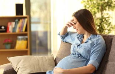 Worried pregnant woman sitting on couch after car accident