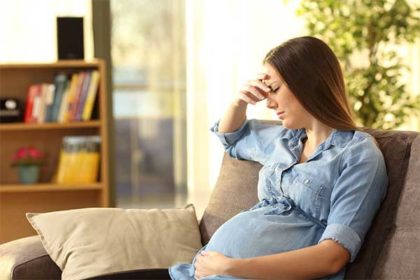 Worried pregnant woman sitting on couch after car accident