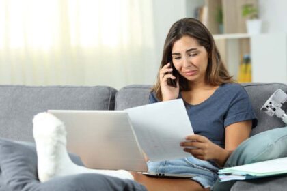 Injured woman on couch looking at medical bills
