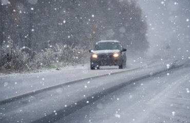 Car driving on Kansas winter road in snowy conditions.