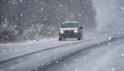 Car driving on Kansas winter road in snowy conditions.