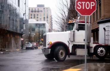 Semi-truck turning at stop sign on a downtown city street.
