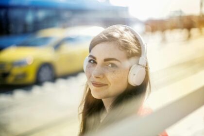 Young female with headphones walking to car. Young female with headphones walking to car.